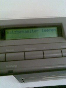 Foto eines HP-Laserdruckers mit dem Text "Satzbehälter Leeren" auf dem Display